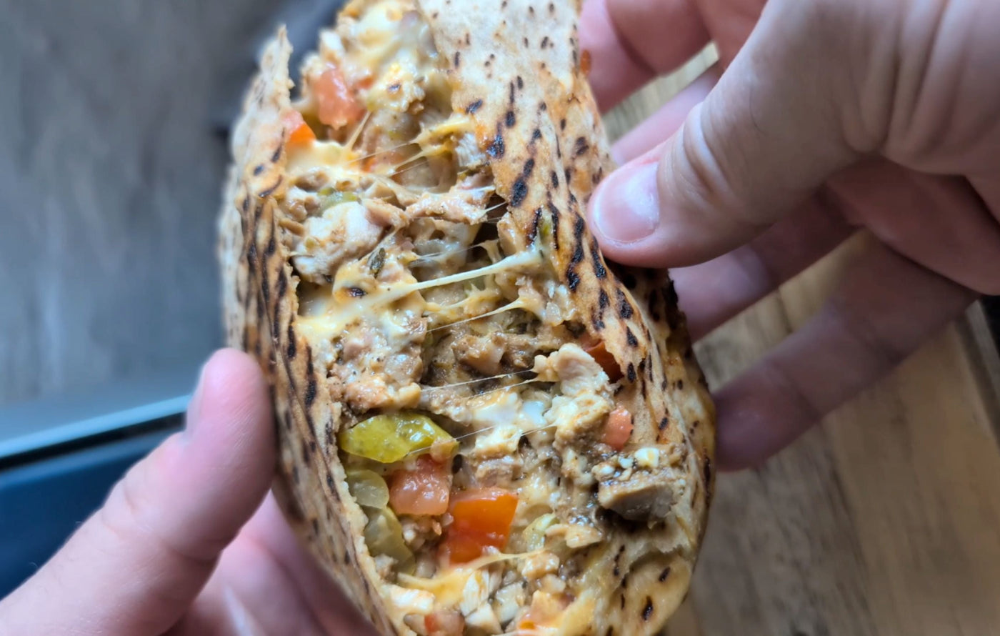 Toasted shawarma pocket filled with spiced chicken, melted cheese, pickles, and tomato, drizzled with creamy tzatziki sauce.