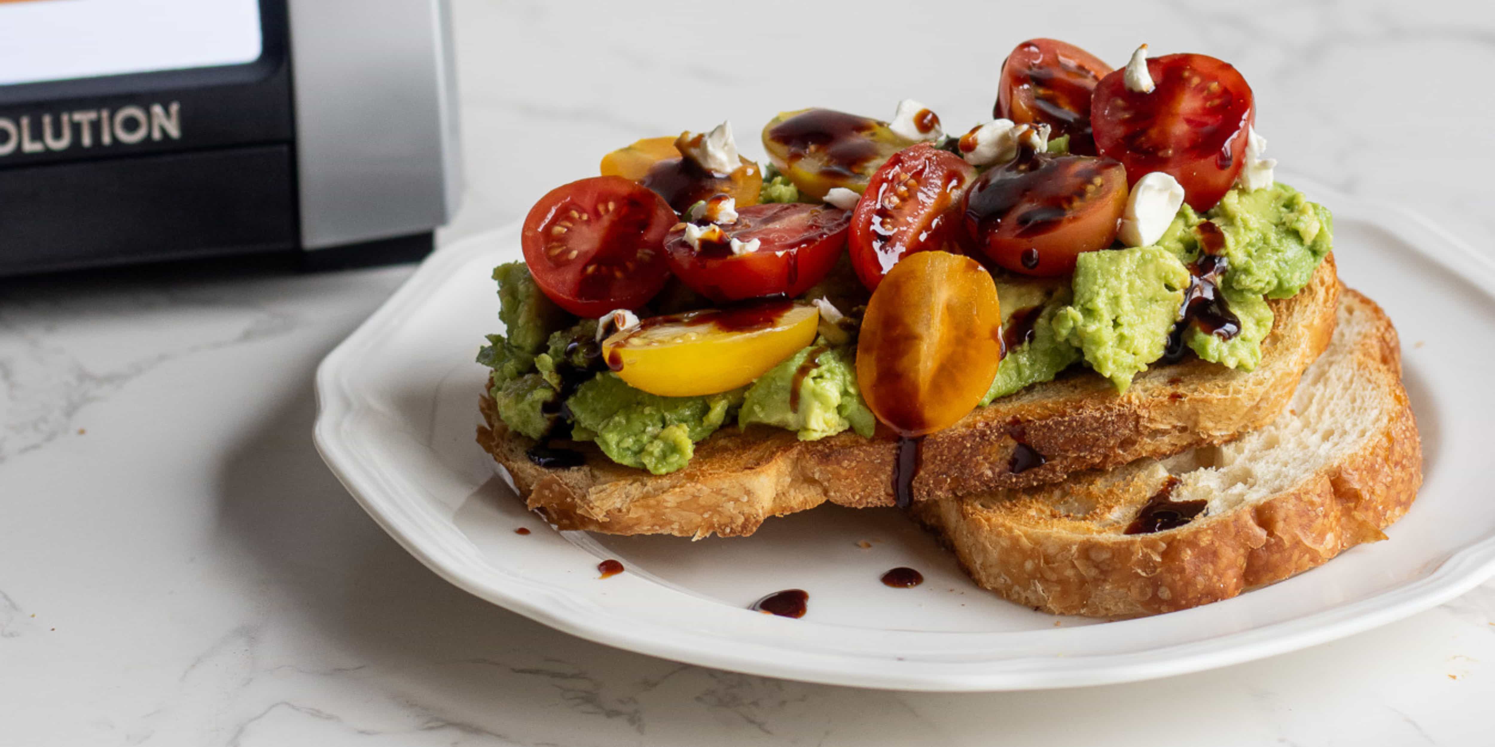 perfectly golden toast with avocado, tomato, feta and balsamic on a white plate