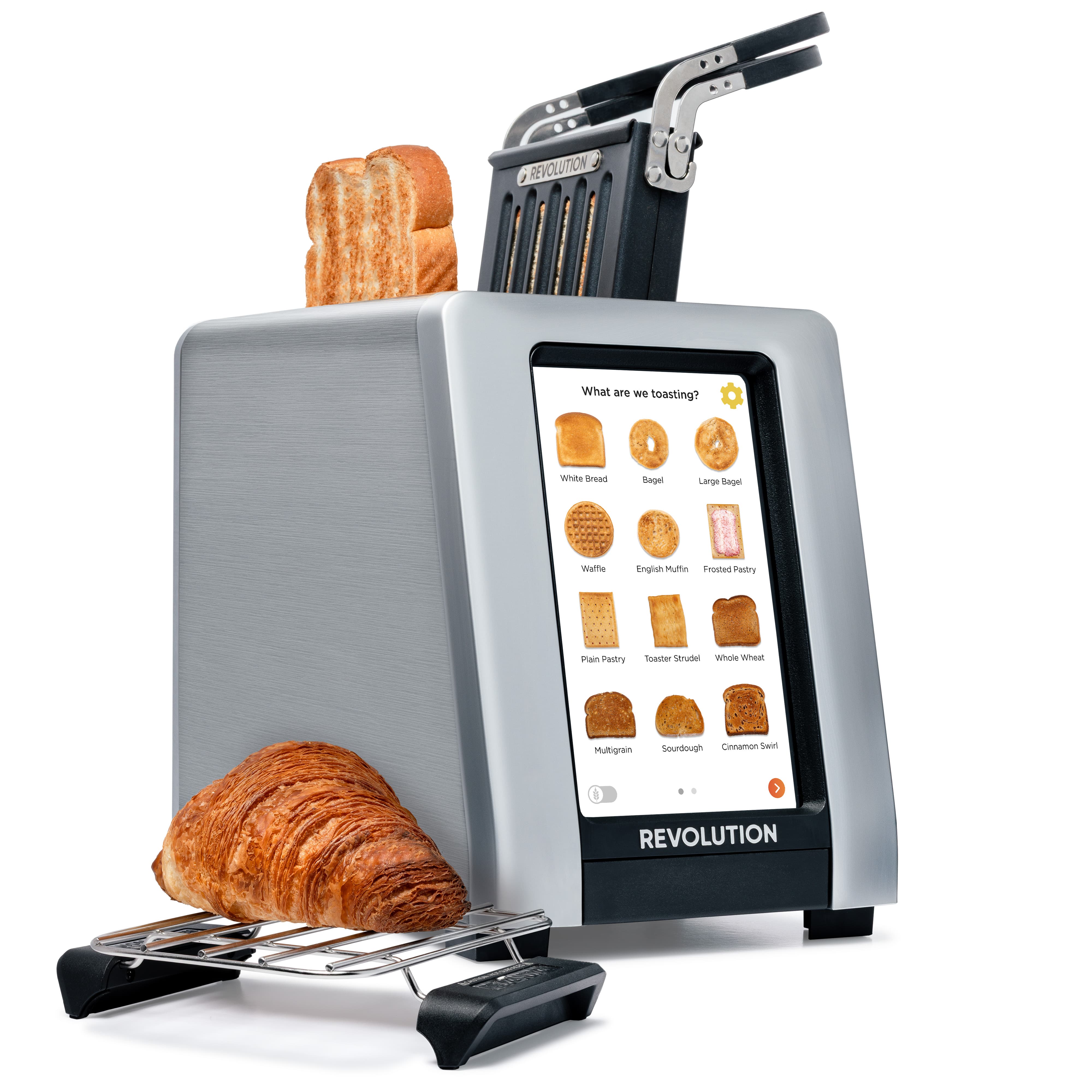 The Revolution Cooking R180 Connect Plus Smart Toaster features a touchscreen display with bread options. Slices of bread are toasting, while a croissant sits on the warming rack, alongside the included Toastie Press.