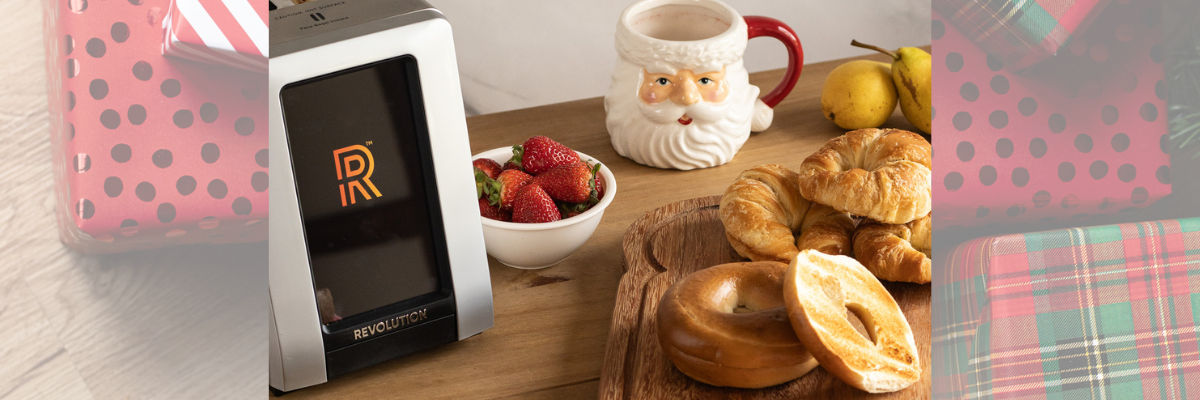 Revolution Cooking smart toaster surrounded by food on a wooden countertop.