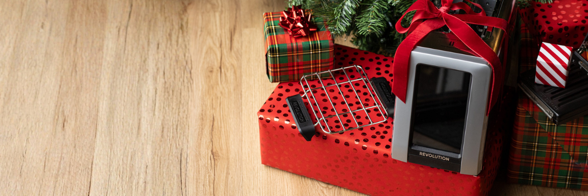 Revolution Cooking smart toaster and warming rack with a bow under the Christmas tree with gifts around it.