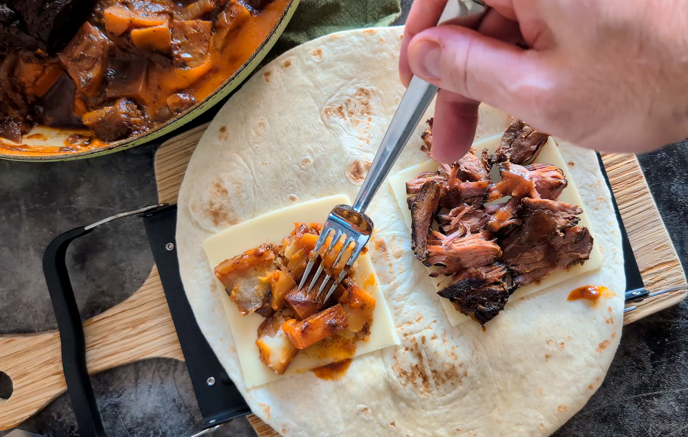 A folded pot roast burrito made in the Revolution Toastie Press™, showing melted cheese, shredded beef, and toasted tortilla.