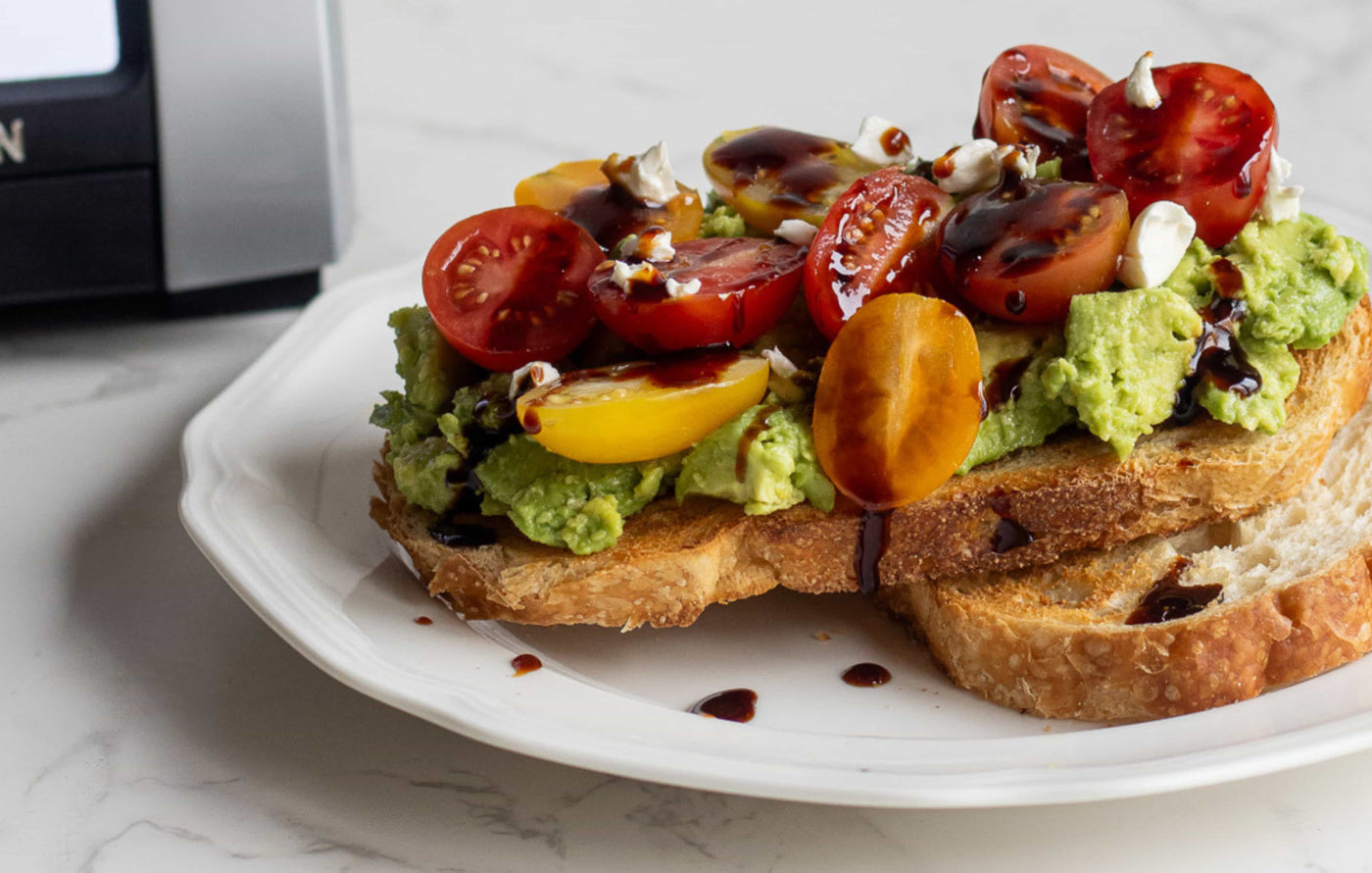 perfectly golden toast with avocado, tomato, feta and balsamic on a white plate
