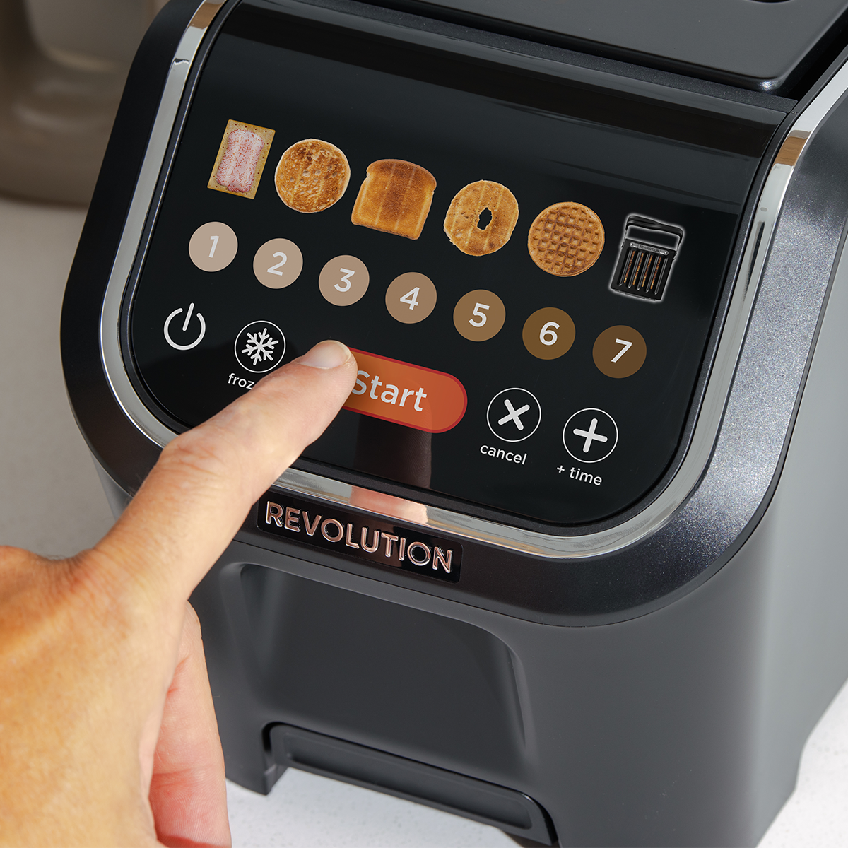 Close-up of a person pressing a circular button on a sleek toaster with a touchscreen. The display features images of various bread types with numbered settings, and options for frozen, cancel, and time adjustment.