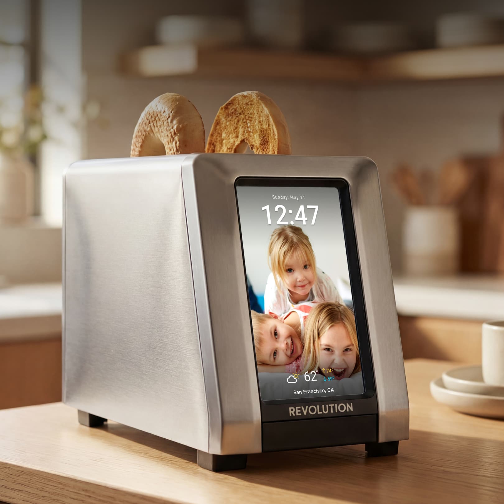 The Revolution Cooking R180 Connect Plus Smart Toaster features a Wi-Fi touchscreen display that shows time, date, weather, and family photos—much like a digital photo frame—while toasting two bagels on your kitchen counter.