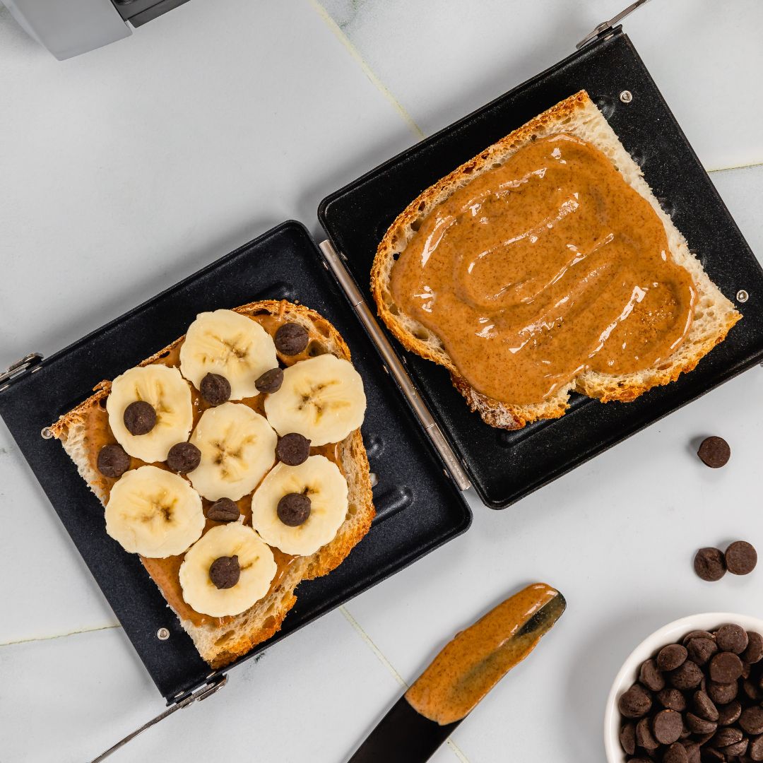 Open faced peanut butter, banana, and chocolate chip in panini press accessory. 